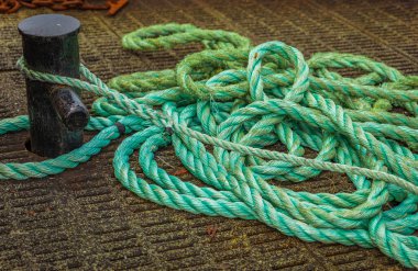 Mooring Bollard with rope on pier by the sea. Green Port rope. Mooring rope. Rope for fastening ships and cargo. Nobody