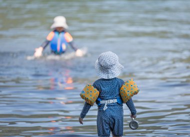 Two year old toddler boy wearinig swimmies arm floats playing in a water, sea, lake. Small child enjoying vacation by the sea, ocean. Travelling with kids. Copy space-July 26,2022-Vancouver BC Canada