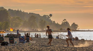 Freinds playing beach volleyball having fun in sporty active lifestyle. Young people playing volleyball on beach at sunset. Living healthy lifestyle doing sport on beach-July 24,2022-Vancouver Canada