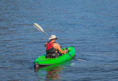 Senior man practicing kayaking. Summer landscape, a man fisherman floats on an inflatable boat on the Cultus lake British Columbia, Canada-July 26,2022. Travel photo, summer water sport activity,