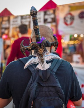 Man with a sword. Person walking with cosplay sword on a street. Warcraft arthas cosplay sword. Street photo, travel photo, blurred