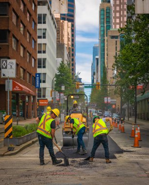 İşçiler, sıcak asfaltı yola koydular. Koruyucu üniformalı küreklerle yol inşaat işçileri. 10 Temmuz 2022-Vancouver Kanada 'da Road İnşaat İşletmeleri. Sokak fotoğrafı