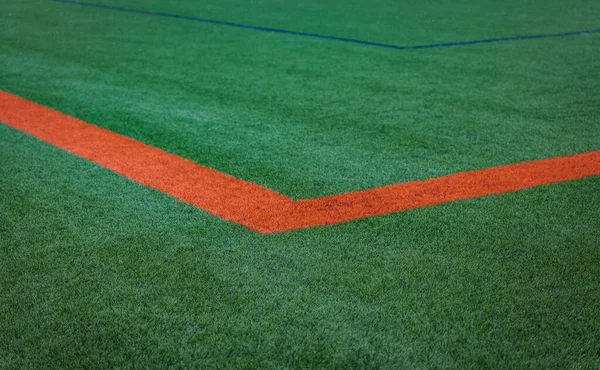 Orange stripe on the green soccer field from top view. Green empty football field. Surface of Artificial turf with orange corner line on the green football or soccer field. Nobody, copy space for text