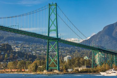 Lions Gate Bridge in summer day, Vancouver, BC, Canada. View of Lions Gate Bridge from Stanley Park. Built in the 1930s, Vancouver's Lions Gate Bridge spans across Burrard Inlet to the Northshore clipart