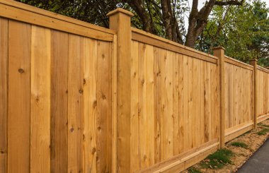 Nice new wooden fence around house. Wooden fence with green lawn. Street photo, nobody, selective focus