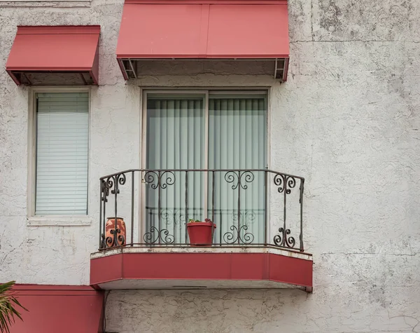 Beautiful old house with windows and balcony with flower pots. White house facade with red color door and windows. Nobody, street view, travel photo
