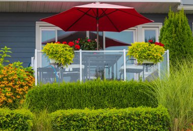 Çiçekler, evin önündeki güzel budanmış çalılar, ön bahçe. Peyzaj tasarımı. Çiçeklerle dolu güzel bir balkon. Hiç kimse, sokak fotoğrafı.