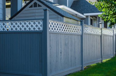 Nice new wooden fence around house. Wooden fence with green lawn. Street photo, nobody, selective focus