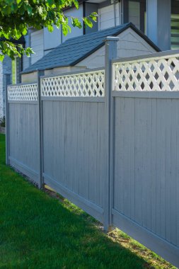 Nice new wooden fence around house. Wooden fence with green lawn. Street photo, nobody, selective focus