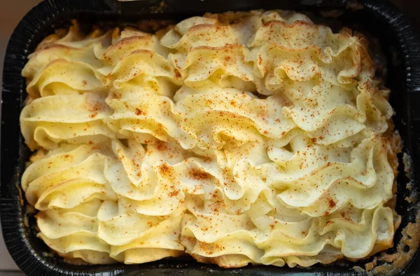 Shepherd\'s pie. Minced meat, mashed potatoes and vegetables casserole in cast iron pan. Top view. Shepherd\'s Pie or Cottage Pie popular dish in United Kingdom and Ireland. Nobody, selective focus