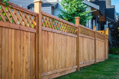 Nice new wooden fence around house. Wooden fence with green lawn. Street photo, nobody, selective focus