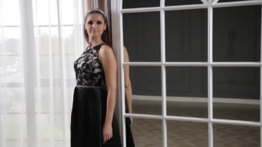 Siyah elbiseli güzel bir kadın pencerenin yanındaki aynada kendine hayran.. 