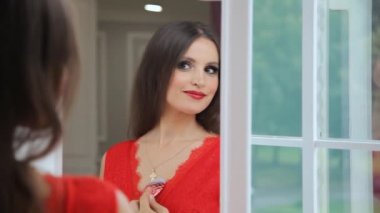 Kırmızı elbiseli güzel bir kadın pencerenin yanındaki aynada kendine hayran.. 