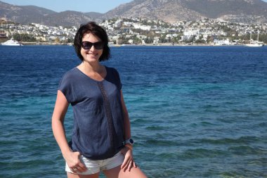 Güzel kız deniz arka plan üzerinde kamera için poz. Model yaz gün sahilde poz.