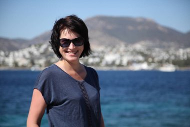 Güzel kız deniz arka plan üzerinde kamera için poz. Model yaz gün sahilde poz.