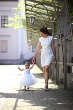 KYIV, UKRAINE - 18 Haziran 2022 Beyazlı iki güzellik. Annesi ve küçük kızı beyaz elbiseli. Çocukluk ve annelik. Anne ve küçük kızı yürüyüşe çıktı. Editör imajı.