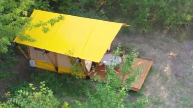 Budget glamping for family outdoor recreation. Glamping terrace in the forest. Glamping houses, rural landscape, tent houses.