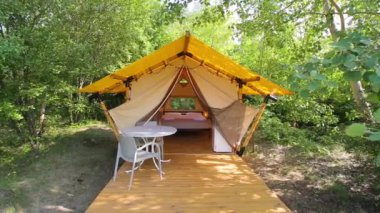 Budget glamping for family outdoor recreation. Glamping terrace in the forest. Glamping houses, rural landscape, tent houses.