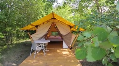 Budget glamping for family outdoor recreation. Glamping terrace in the forest. Glamping houses, rural landscape, tent houses.