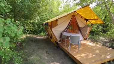 Budget glamping for family outdoor recreation. Glamping terrace in the forest. Glamping houses, rural landscape, tent houses.