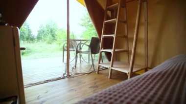 Budget glamping for family outdoor recreation. Glamping terrace in the forest. Glamping houses, rural landscape, tent houses.
