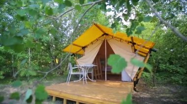 Budget glamping for family outdoor recreation. Glamping terrace in the forest. Glamping houses, rural landscape, tent houses.