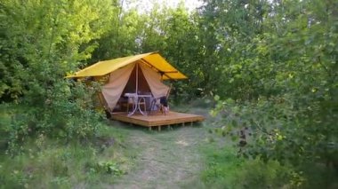 Budget glamping for family outdoor recreation. Glamping terrace in the forest. Glamping houses, rural landscape, tent houses.