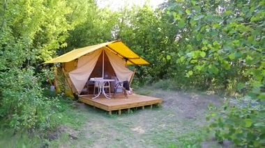 Budget glamping for family outdoor recreation. Glamping terrace in the forest. Glamping houses, rural landscape, tent houses.