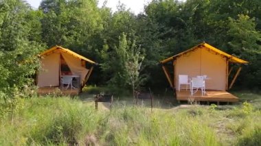 Budget glamping for family outdoor recreation. Glamping terrace in the forest. Glamping houses, rural landscape, tent houses.