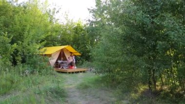 MOGYLIVKA, UKRAINE - AUGUST 21, 2022: Budget glamping for family outdoor recreation. Glamping terrace in the forest. Cute fabric tents, in a forest environment in an eco camp - editorial footage