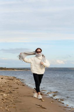 Açık renk ceketli ve Volga kıyısında gri atkısı olan bir kız.