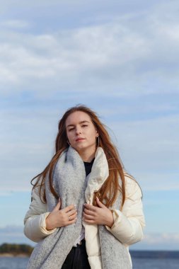 Açık renk ceketli ve Volga kıyısında gri atkısı olan bir kız.