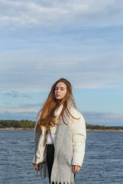 Açık renk ceketli ve Volga kıyısında gri atkısı olan bir kız.
