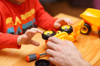 Baba ve oğulun elleri oyuncak arabaları bir araya getiriyor.