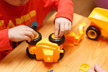 Baba ve oğulun elleri oyuncak arabaları bir araya getiriyor.