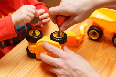 Baba ve oğulun elleri oyuncak arabaları bir araya getiriyor.