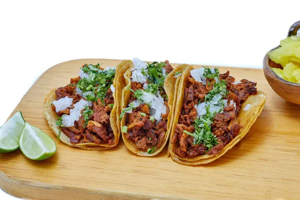 Tacos al pastor, traditional Mexican food, with onion, cilantro, pineapple, red sauce or guacamole.