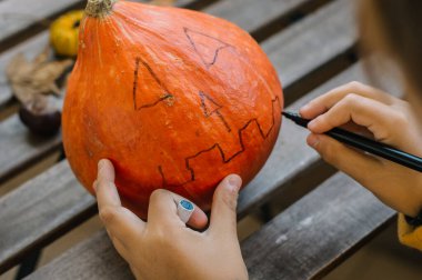Çocuklar Cadılar Bayramı hazırlıkları için canavar balkabağını çiziyor..