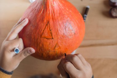 Çocuklar Cadılar Bayramı hazırlıkları için canavar balkabağını çiziyor..