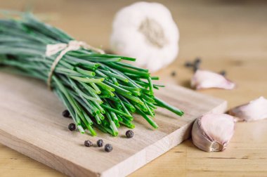 Bir demet taze soğan, sarımsak, ahşap tahtada biber..