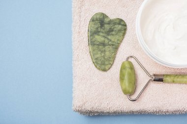 Yüz bakımı ve masaj. Kremalı yüz silindiri ve blu arka planda bir havlu.