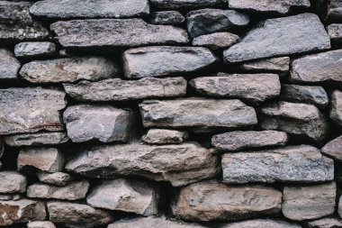 Taş bir duvarın arka planı, yakın plan. Betonda büyük ve küçük çok renkli taşların dokusu.