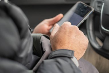 Erkek eller arabanın direksiyonunda akıllı telefonu tutuyor..