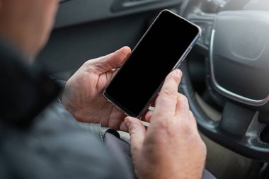 Erkek eller arabanın direksiyonunda akıllı telefonu tutuyor..