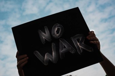 Çocuğun elinde bir poster var. Arka planda savaş yok..