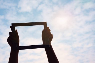 Eller gökyüzünde ve arka planda bir maket posteri tutuyor..