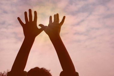 Gün batımına uzanan siluet eller