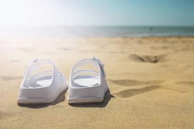 Yaz tatili konsepti. Sahilde bir çift beyaz sandalet.