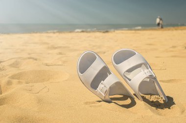 Yaz tatili konsepti. Sahilde bir çift beyaz sandalet.