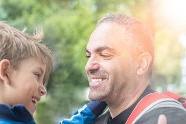 Baba ve oğul, yeşil doğada birlikte sarılıp oynuyorlar..